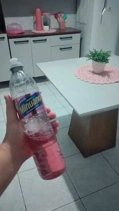 a person holding up a bottle of mineral water in a kitchen with white tile flooring