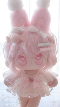 a doll with pink hair and big ears is posed in front of a window,