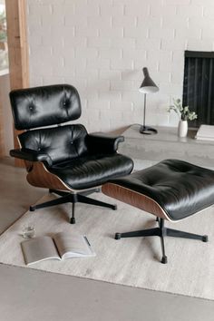 an eames chair and ottoman in a living room with a book on the floor