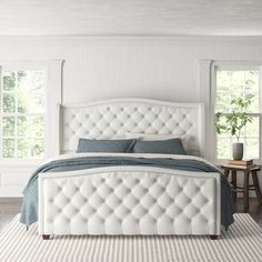 a large white bed sitting in a bedroom next to two small tables and chairs on top of a rug