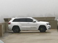 two white jeeps parked next to each other in a parking lot on a foggy day