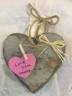 a heart shaped rock with a note attached to it that says love you more hanging on a string