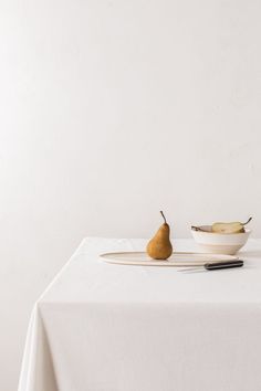 two pears and a plate on a white table cloth