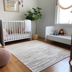 a baby's room with a crib, chair and rug in the corner