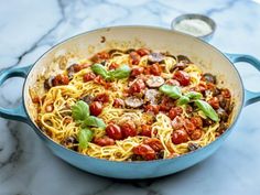 a blue pan filled with spaghetti and tomatoes