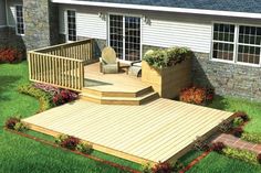 a backyard deck with steps and planters in the grass