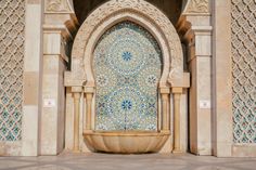 an intricately designed fountain in the middle of a building with blue and white tiles on it