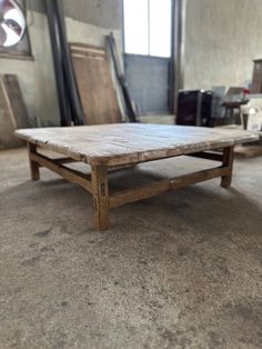 an old wooden table sitting on top of a floor in a room filled with furniture