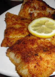 fish fillets with lemon wedges on a white plate