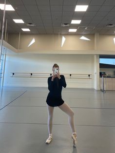 a ballerina is taking a selfie in an empty dance studio with her cell phone