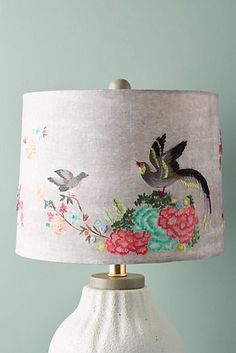 a white lamp with pink flowers on it and a bird painted on the fabric shade