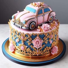 a pink and blue decorated cake with flowers on it's side, sitting on a gold plate