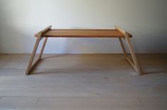 a wooden bench sitting on top of a hard wood floor next to a white wall