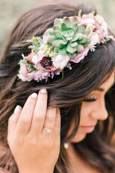 a woman wearing a flower crown with her hands on her head and one hand near her face