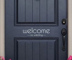 a welcome sign on the front door of a house with pink flowers in pots next to it