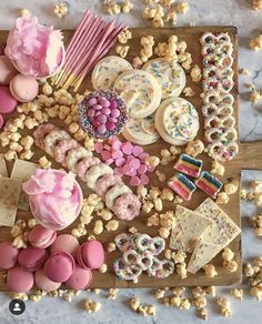 a wooden tray topped with lots of different types of desserts and candy bars on top of a table