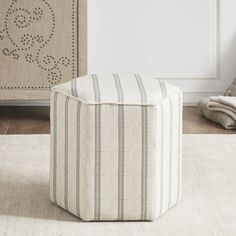 a white and grey striped ottoman sitting on top of a rug next to a dresser