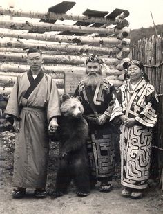 an old black and white photo of three people with a bear in front of them