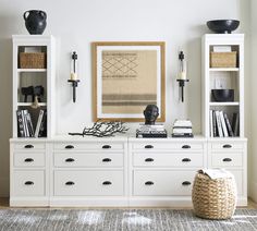 a living room with white furniture and bookshelves filled with books, vases and other items