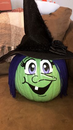 a green pumpkin with a witch hat on it's head sitting on a couch