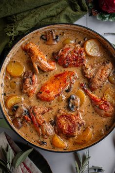 a pan filled with chicken and vegetables on top of a table