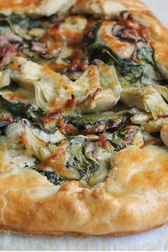 a pizza with spinach and cheese on it is sitting on a piece of paper