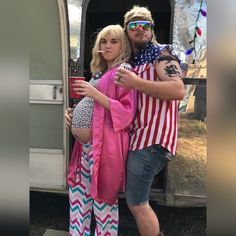 a man and woman dressed in patriotic clothing standing next to an airshow trailer with their arms around each other