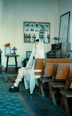 a woman sitting in a church with her veil over her face and shoes on the floor