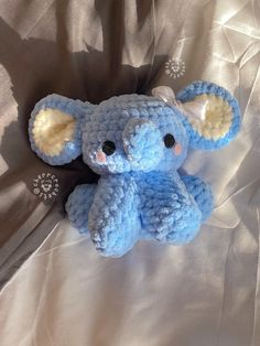 a blue stuffed animal laying on top of a white sheet