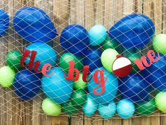 some balloons are hanging on a fence with the words the big one written in red, white and blue