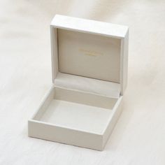 an empty white box sitting on top of a white sheeted surface with the lid open