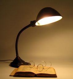 an open book sitting on top of a table next to a light that is turned on