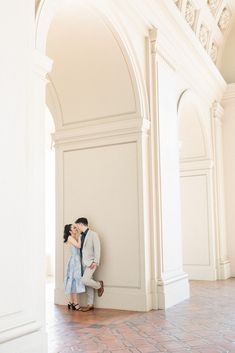 a man and woman are kissing in an arched room with brick flooring on the ground