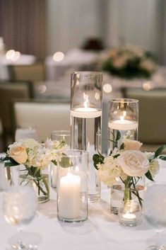 the centerpieces on this table are filled with flowers, candles and glass vases