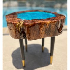 a wooden table sitting on top of a cement floor next to a swimming pool with blue water in it