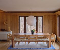 a dining room with wood paneling and large windows