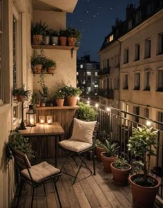 an outdoor balcony with potted plants and candles on the table, along with two chairs