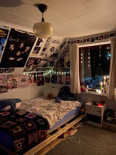 a bedroom with posters on the wall and a bed in front of a window filled with lights