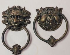 two metal door knockets with faces on them, one in the shape of a lion's head