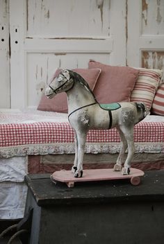 a toy horse on top of a skateboard in front of a couch and bed