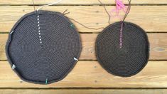 two black hats are hanging on a wooden table with string and thread attached to them