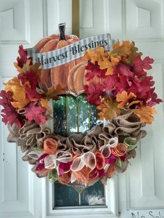 a wreath with fall leaves and pumpkins hanging on the front door to welcome guests