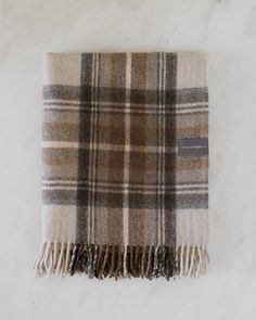 a tan and black plaid blanket on a white surface