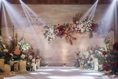 an aisle decorated with flowers and candles for a wedding or special event in front of a large painting