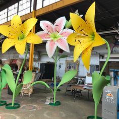 three large yellow and pink flowers are in the middle of a room with other furniture