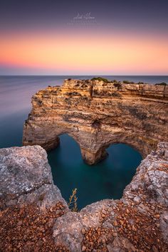 the ocean is blue and clear with rocks in front of it that are shaped like an arch