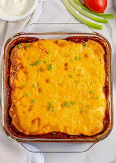 a casserole dish with cheese and vegetables on the side