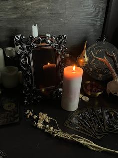 a table topped with candles and cards next to a mirror on top of a wooden wall