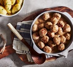 a bowl filled with meatballs next to a wooden spoon