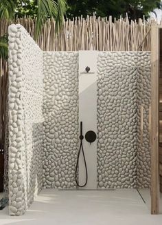 an outdoor shower in the middle of a garden area with palm trees and white pebbles